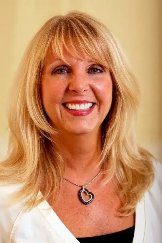 An elderly woman with long, healthy blonde hair smiling and winking, showcasing the benefits of TruVarin Hair Growth Supplement.