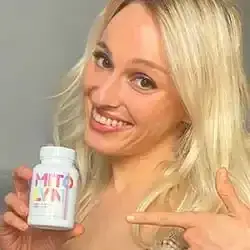 Smiling blonde woman holding a bottle of Mitolyn weight loss supplement and pointing at it.